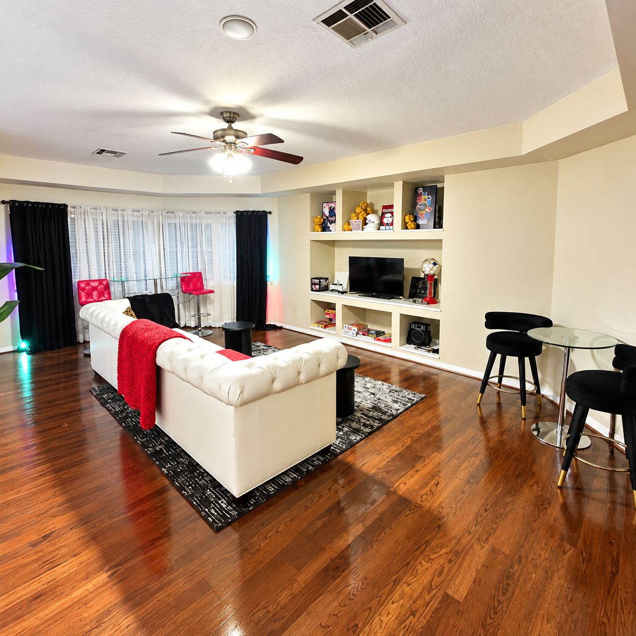 The game room with a white tufted sofa, TV and bistro table